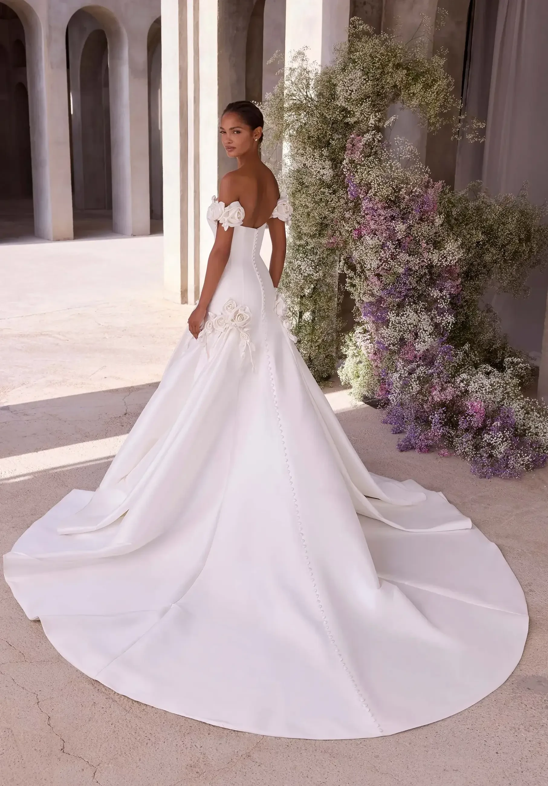 Model is wearing a wedding gown adorned with 3D floral appliques for a textured, romantic look.