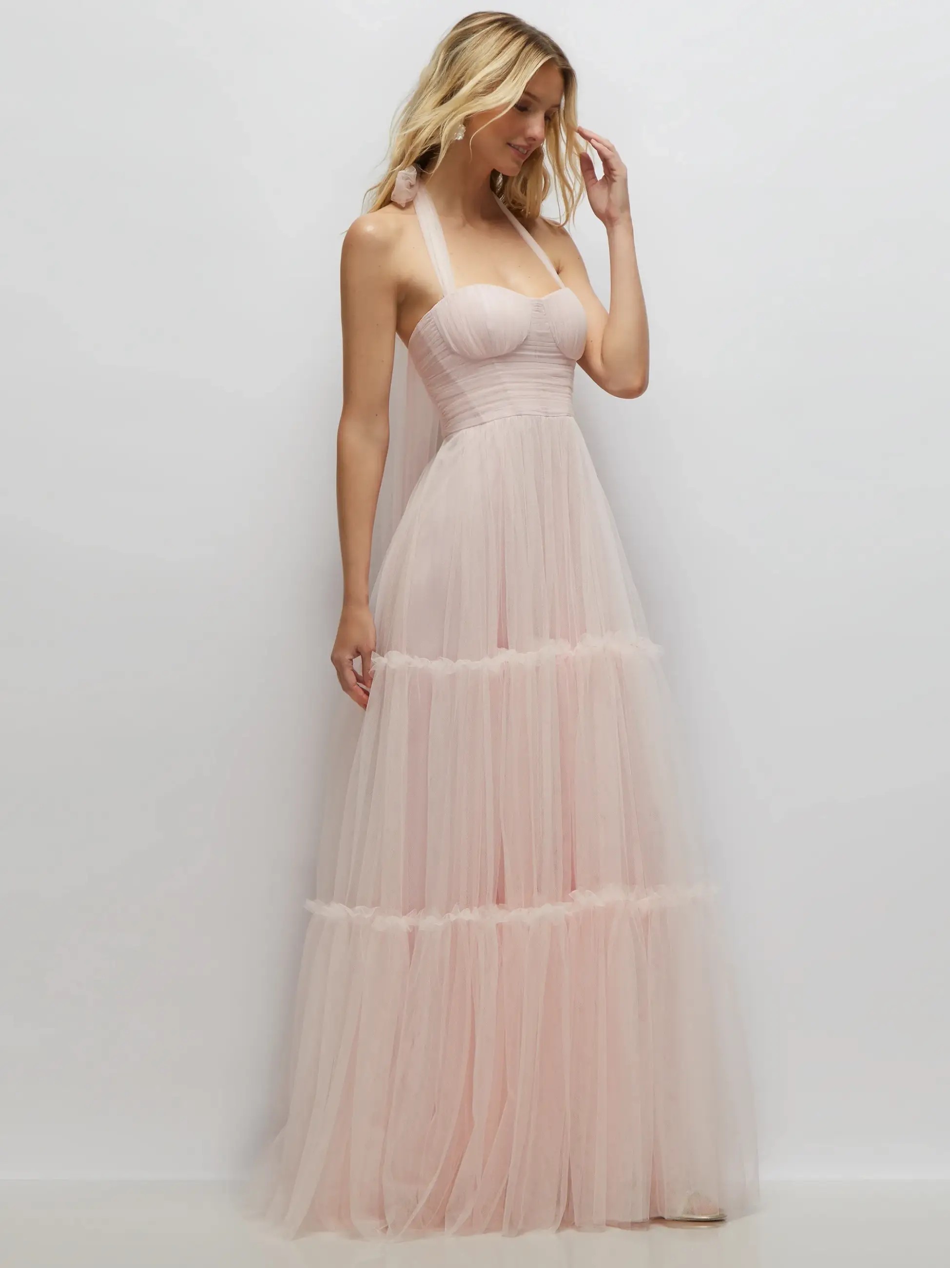 Model is wearing a halter light pink tulle dress with a sweetheart neckline and a-line silhouette