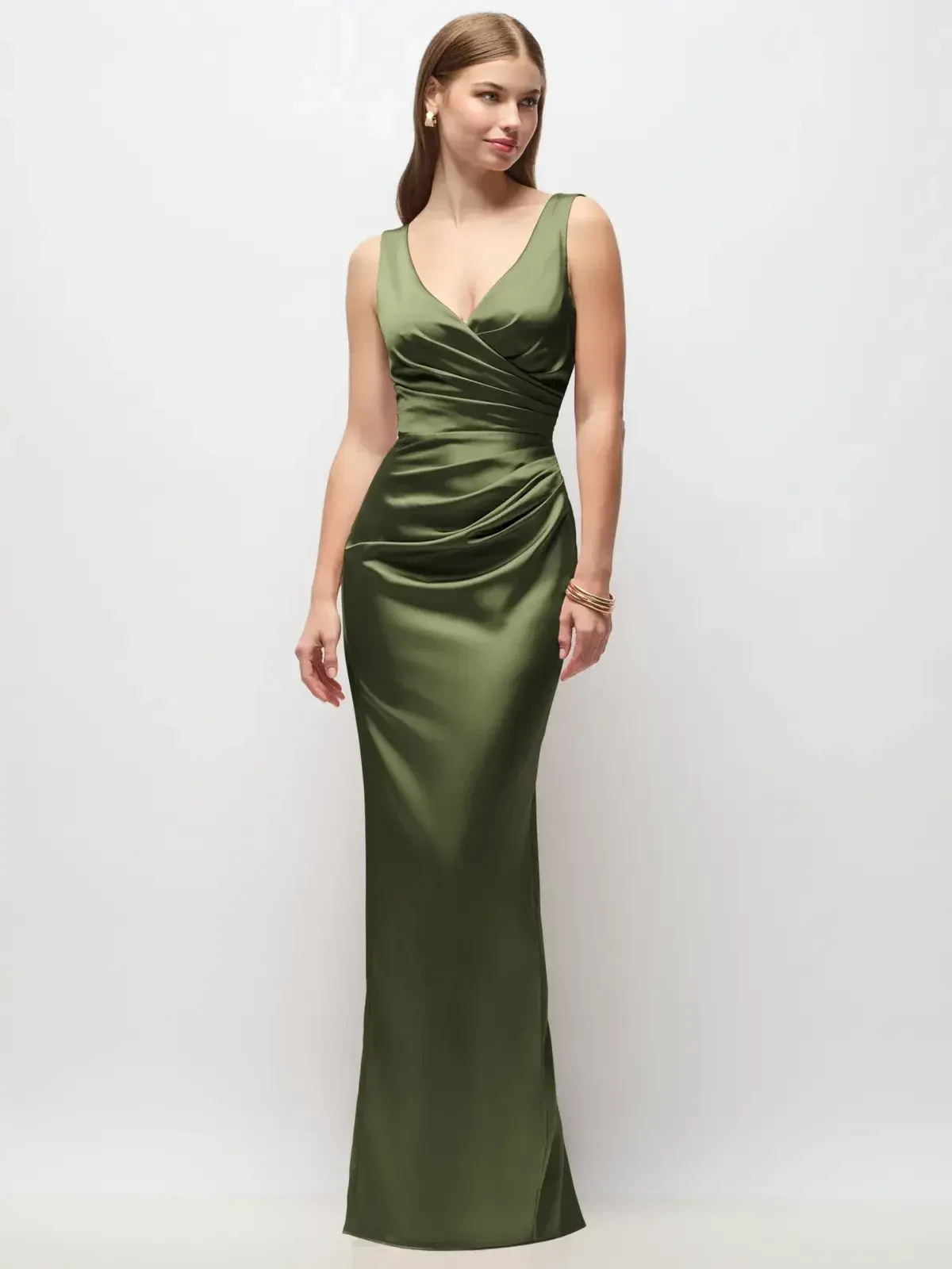 A woman wearing a form-fitting green satin gown with a deep V-neck and draped detailing, standing in a neutral background.