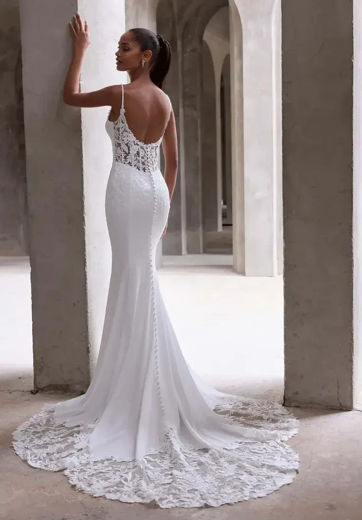 Model is wearing an open back fit and flare lace wedding dress with spaghetti straps