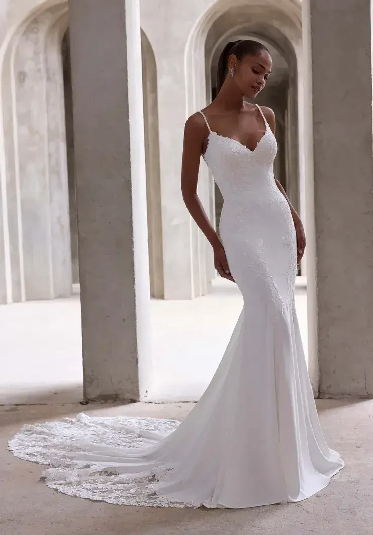 Model is wearing an open back fit and flare lace wedding dress with spaghetti straps