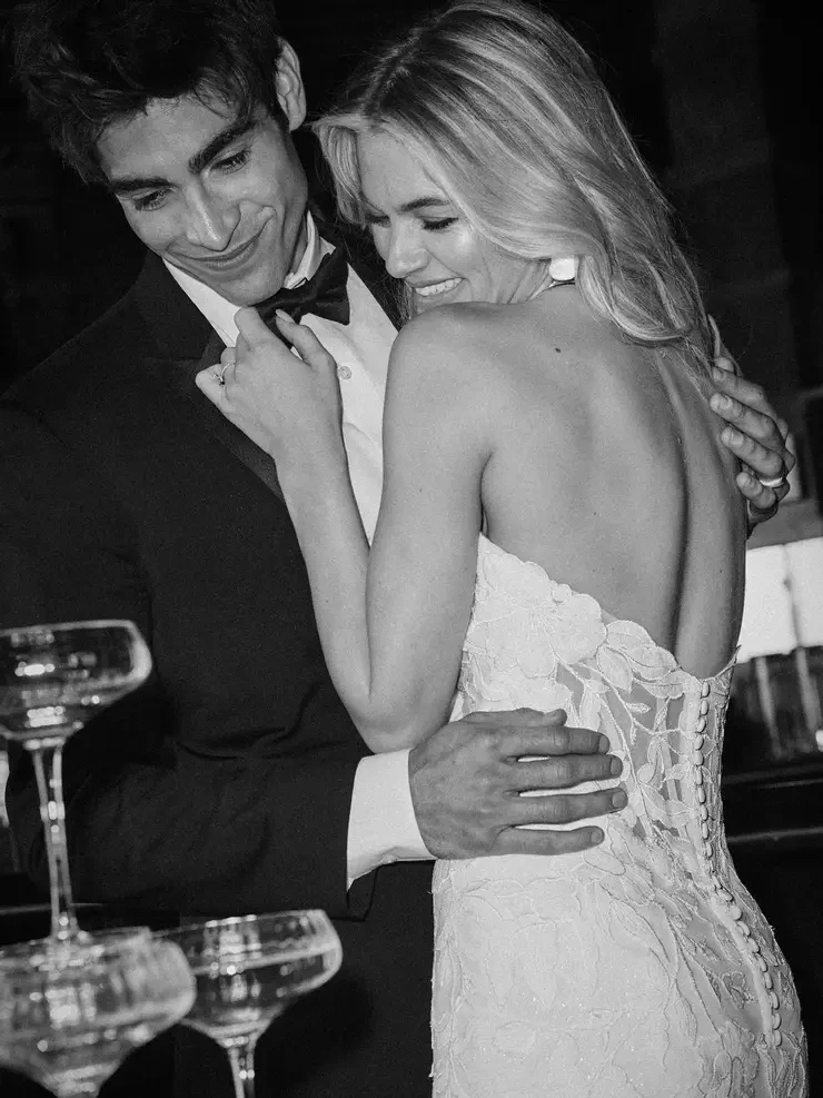 Model is wearing an open back fit and flare bridal gown with a long lace train 