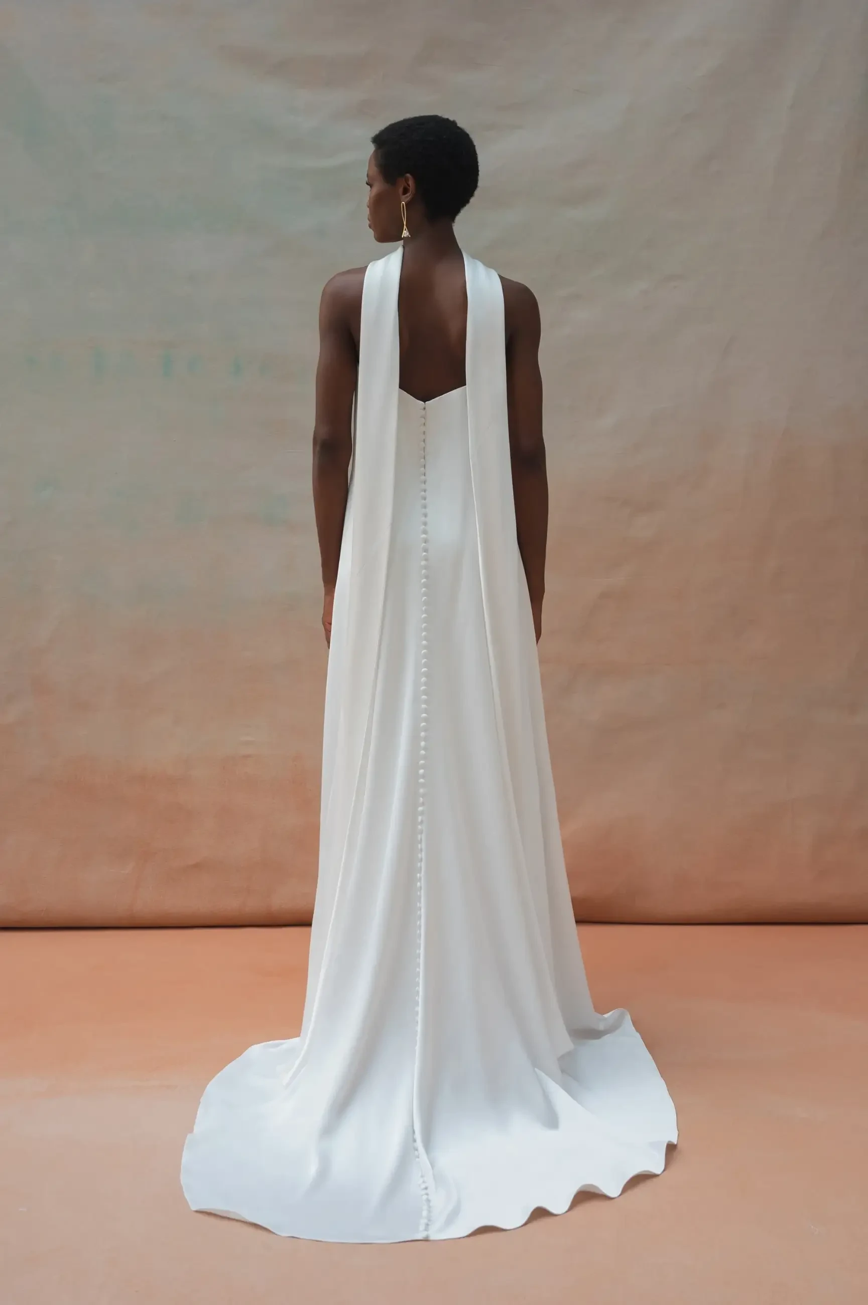 Model is wearing a strapless minimalist loose wedding dress with a bridal neck scarf draped around her neck