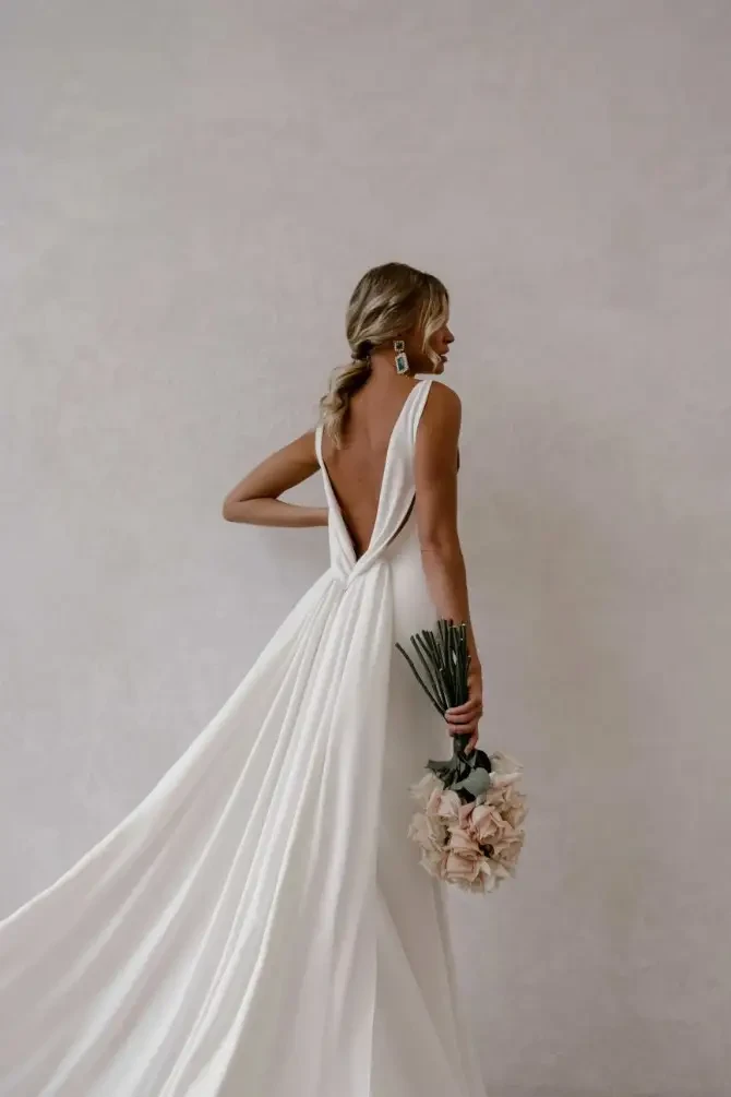 Model is wearing a v-neck open back minimalist wedding dress by made with love