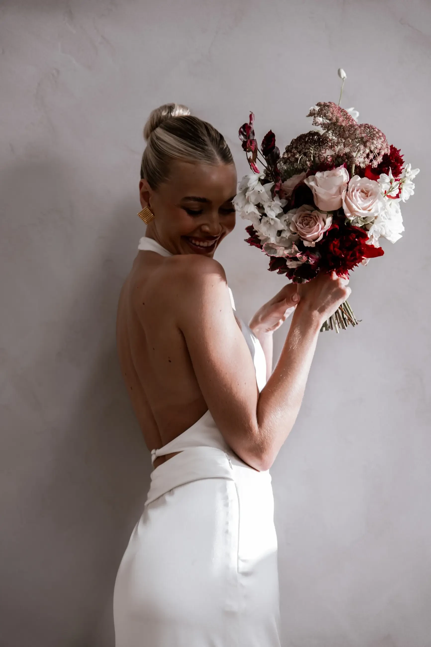 Model is wearing a silky halter high neckline wedding dress