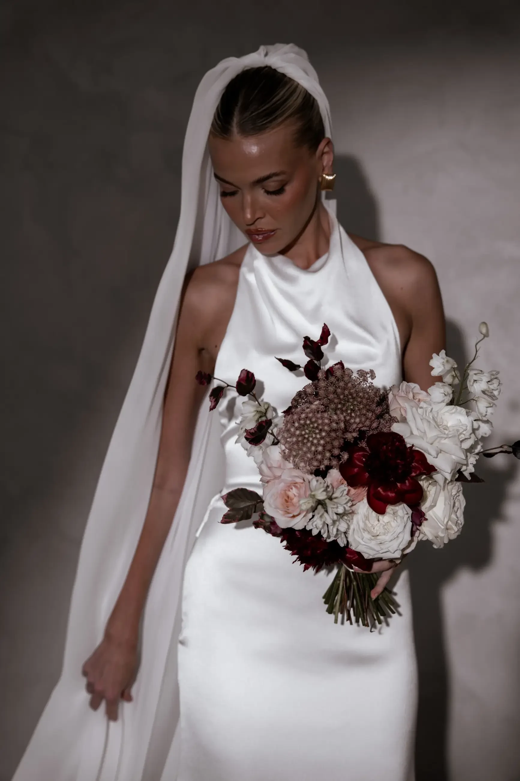 Model is wearing a silky halter high neckline wedding dress