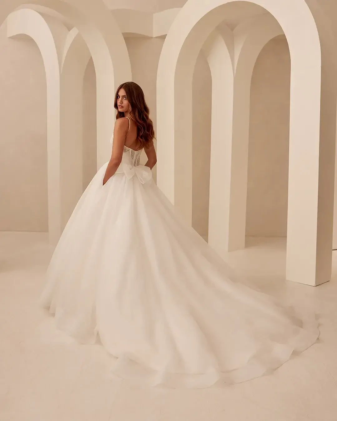 Model is wearing a sleeveless ball gown with a corset bodice and scoop neckline
