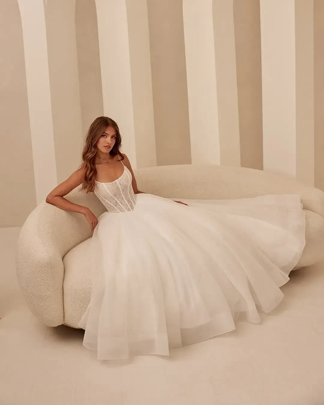 Model is wearing a sleeveless ball gown with a corset bodice and scoop neckline