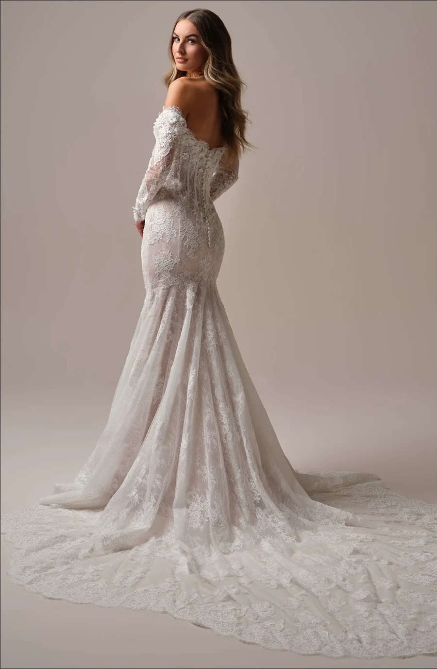 Model is wearing a wedding gown featuring a basque waist that creates a romantic, hourglass shape.